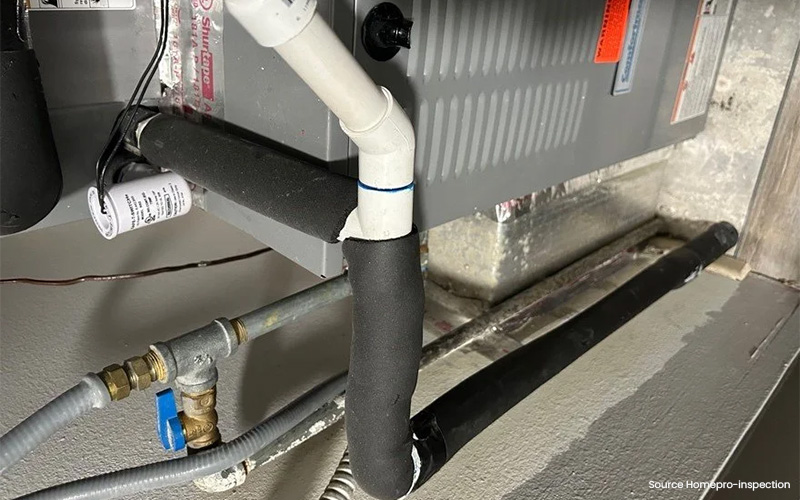 Close-up of HVAC drain and refrigerant lines with insulation, shut-off valve, and conduit.