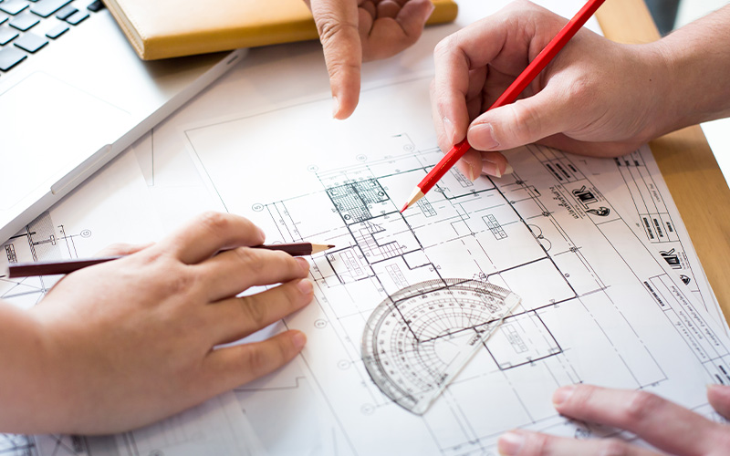 Two people collaborating on a house floor plan drawing