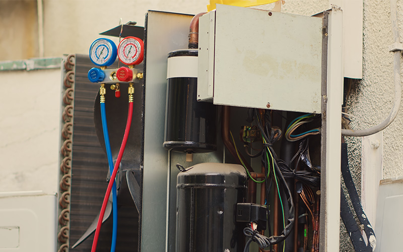 Aircon technician using manifold gauge to check refrigerant levels