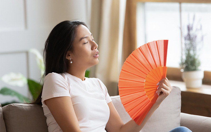 Woman fanning herself due to a broken aircon capacitor.